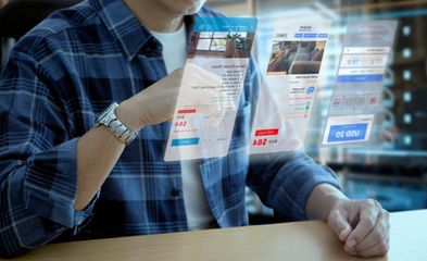 Mann in Freizeitkleidung bei der Interaktion mit einem futuristischen virtuellen Bildschirm einer Anwendung zur Hotelreservierung und Reiseplanung